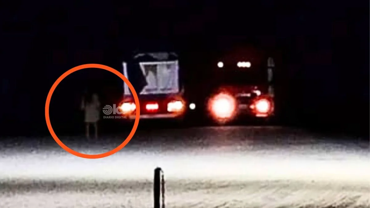 En la imagen se distingue con claridad la silueta de una mujer de espaldas, quieta sobre la ruta, mientras varios camiones contin&uacute;an su marcha a pocos metros.